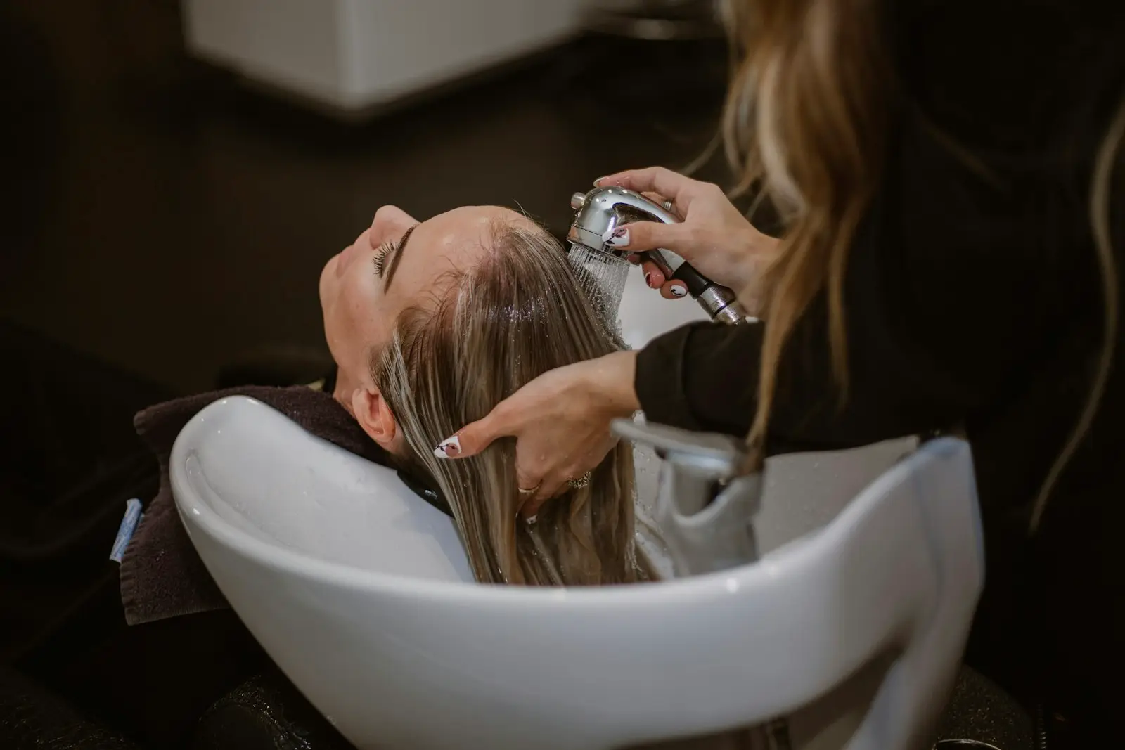 Une cliente se fait faire un shampoing au bac