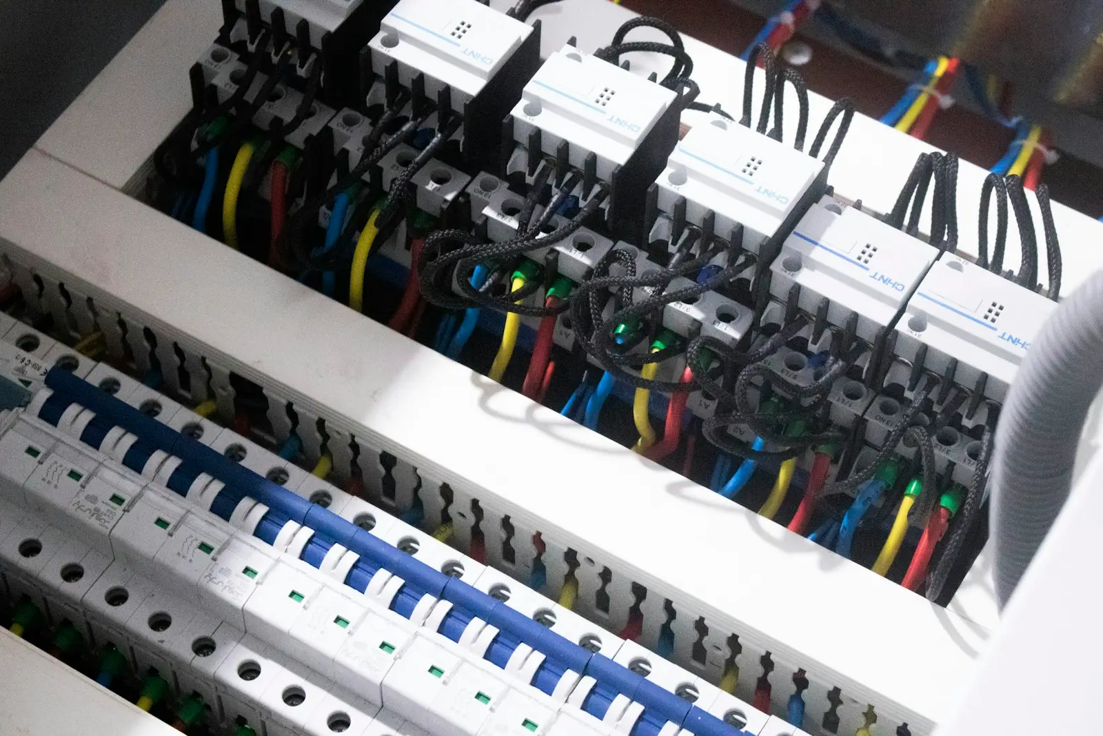 Rangée de disjoncteurs dans un tableau électrique, avec un câblage coloré et bien ordonné